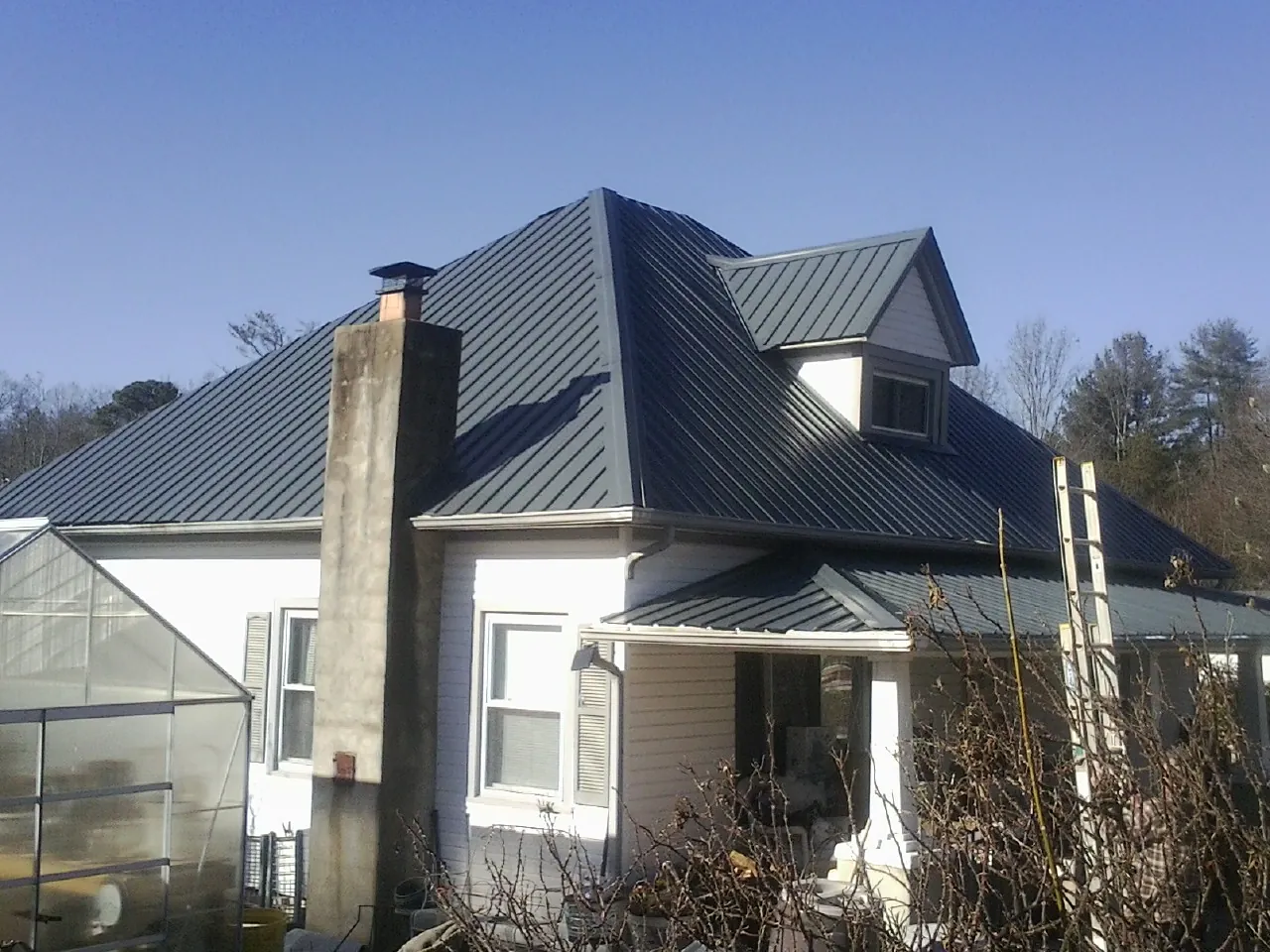 Dark blue standing seam metal roof on a white farmhouse with dormer — Slate & Tile Roof Repair by Roofing Brothers in Bonnieville