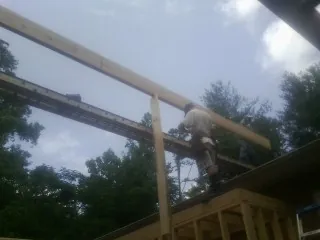 Carpenter setting a ridge beam over a new addition frame — Ice Dam Removal by Roofing Brothers in Bonnieville