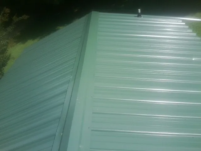 New green metal panels meeting at the ridge of a roof — Flat Roof Repair work by our crew in Bonnieville