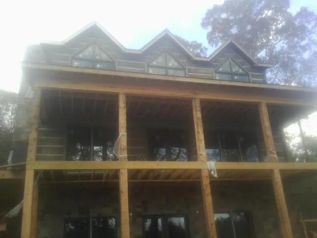 Dormers and porch framing on a large log home under construction — Roof Coating work by our crew in Bonnieville