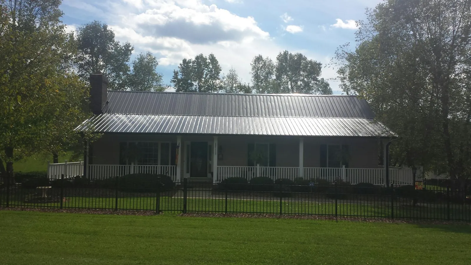 Gray metal roof on a brick ranch with a full width front porch — Gutter Guard Installation work by our crew in Bonnieville