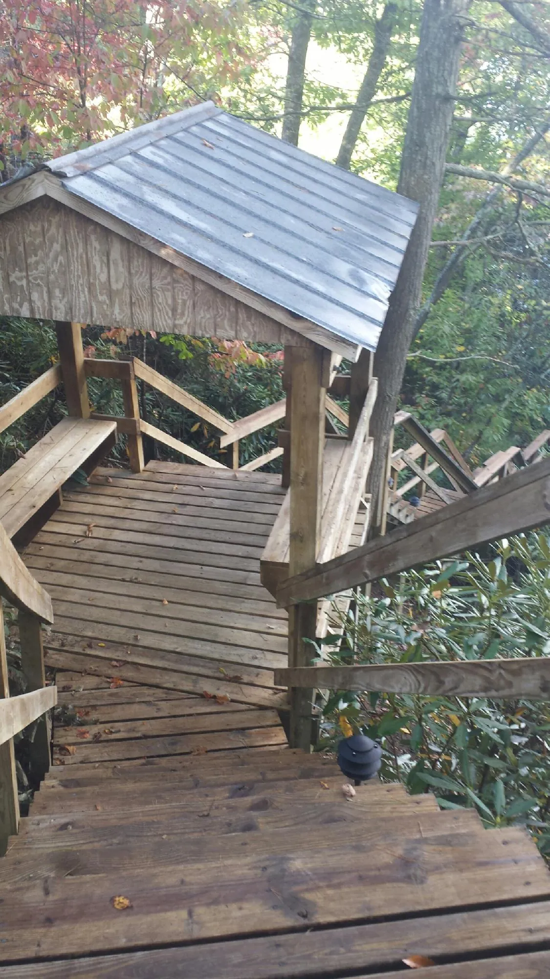 Metal roofed shelter over wooden steps on a wooded walkway — Skylight Repair & Installation work by our crew in Bonnieville