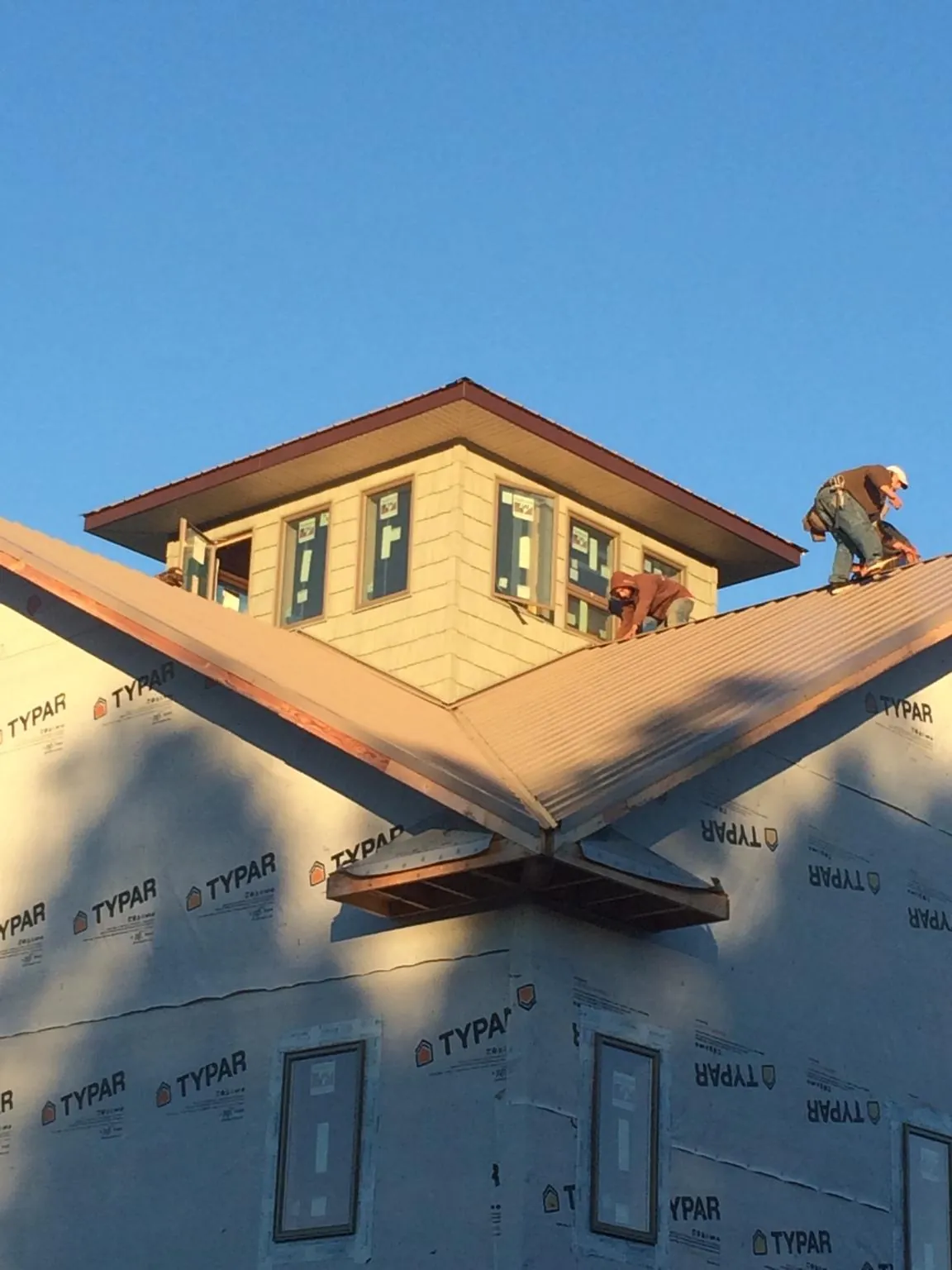 Roofers working around a rooftop cupola on a new metal roof at sunset — Roof Waterproofing in Bonnieville by Roofing Brothers